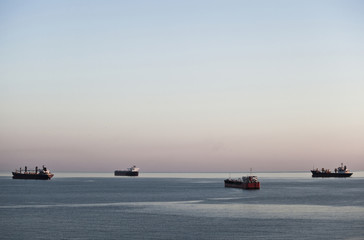 Four cargo ships at anchor on calm sea