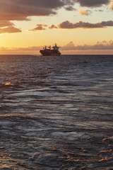 Obraz premium Cargo ship underway at sunset
