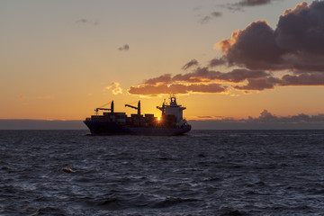 Cargo ship underway at sunset