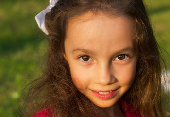 portrait of сute little girl outdoors with curly hair