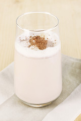 Glass of chocolate-cream cocktail on wooden table close-up