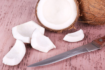 Broken coconut with knife on wooden background