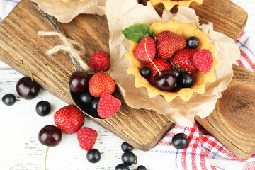 Tasty tartlets with berries on wooden table