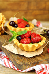 Tasty tartlets with berries on wooden table