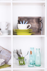 Kitchen utensils and tableware on beautiful white shelves