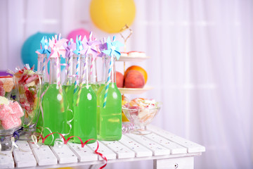 Bottles of drink with straw and sweets on decorative background