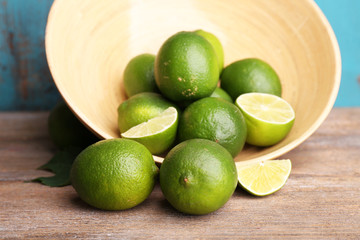 Fresh juicy limes in bowl on old wooden table