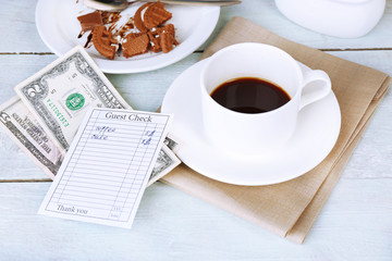 Check, money and remnants of food and drink on table close-up