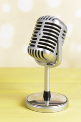 Vintage microphone on table on light yellow background