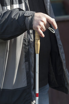 Close up in blind man's hands holding a stick