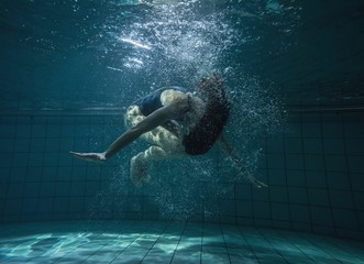 Athletic swimmer doing a somersault underwater