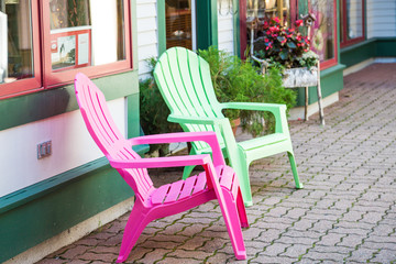 Fototapeta na wymiar Pink and Green Chairs on Town Sidewalk