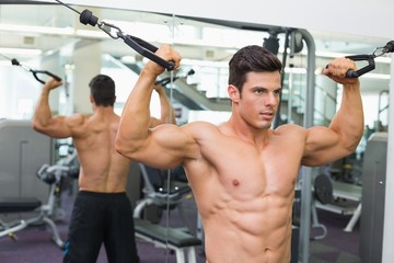 Fototapeta na wymiar Shirtless muscular man using resistance band in gym