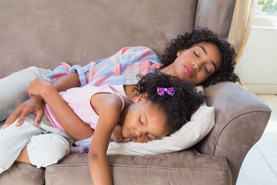Pretty mother sleeping with her daughter on the couch
