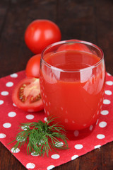 Tomato juice in glass, on wooden background