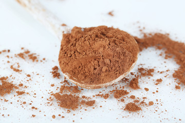 Cocoa powder in spoon isolated on white