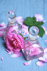 Rose oil in bottles on color wooden background