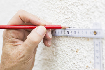 Handwerker arbeitet mit Meterstab und Bleistift