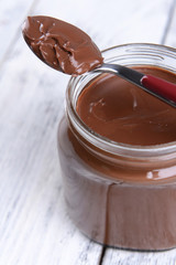 Sweet chocolate cream in jar on table close-up