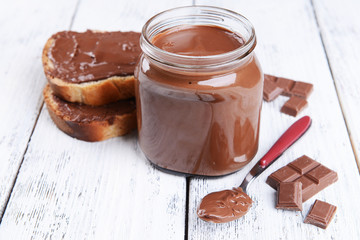 Sweet chocolate cream in jar on table close-up