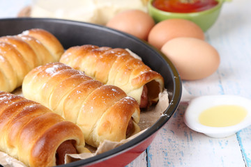 Baked sausage rolls in pan on table close-up