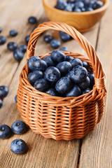 Delicious blueberries in wicker basket on table close-up