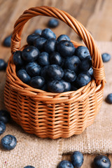 Delicious blueberries in wicker basket on table close-up