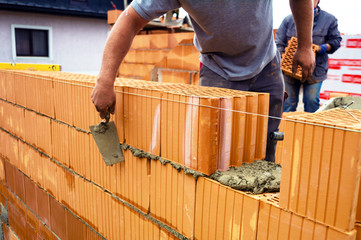 Maurer mit Ziegelmauer auf Baustelle