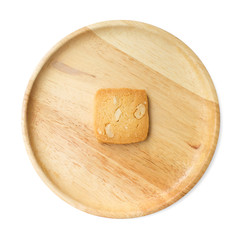 A piece of cashew nut cookie on a wooden plate and white backgro