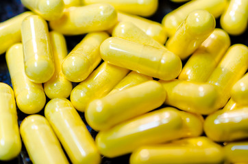 yellow capsules macro closeup on black plate