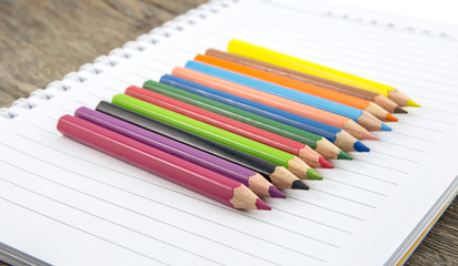 Fototapeta premium Blank paper and colorful pencils on the wooden table.