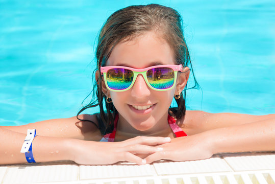 Girl smiling at the edge of a swimming pool