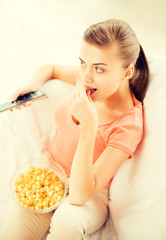 Naklejka premium woman watching tv and eating popcorn