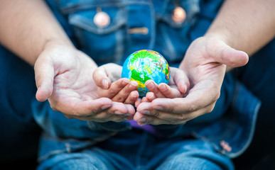 photo of man holding girls hands with earth globe