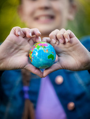 smiling girl holding globe in hands folded in shape of heart