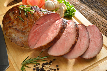 Sliced grilled meat with vegetables on wooden background