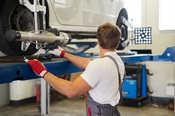 Young serviceman checking wheel alignment  in a car workshop