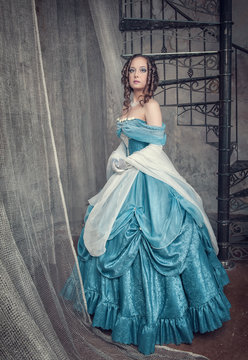 Beautiful woman in blue medieval dress on the stairway