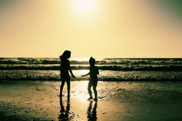 two happy kids playing on the beach at sunset