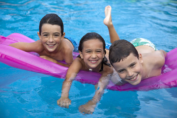 Niños jugando en la piscina en colchoneta fucsia - obrazy, fototapety, plakaty