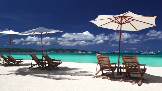 Sun umbrellas and beach chairs on coastline with white sand. Bor