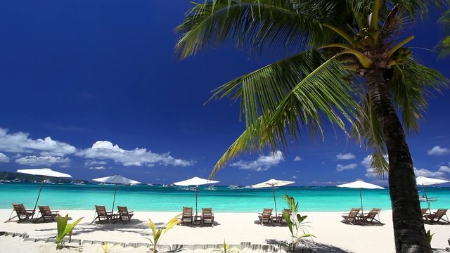 Sun umbrellas and beach chairs on coastline with white sand. Bor
