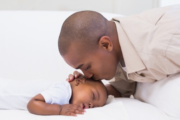 Adorable baby boy sleeping while being watched by father