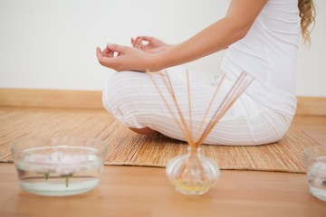 Peaceful woman sitting in lotus pose on bamboo mat