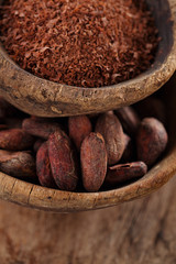 cocoa beans and grated dark chocolate in old texured spoons bowl