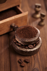 grated coffee in old iron weights and wooden  background