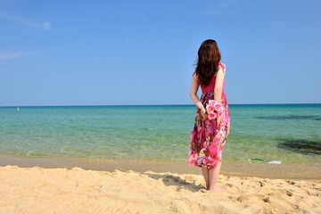 海を眺めるピンクのドレスを着た女性の後ろ姿