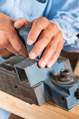 Carpenter's Hands Shaving Wood With Electric Planer