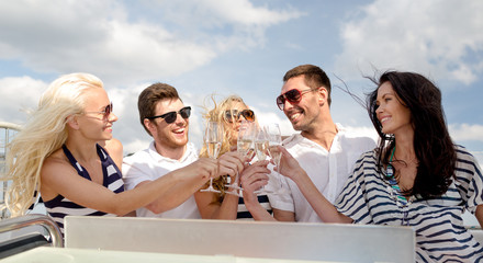 smiling friends with glasses of champagne on yacht