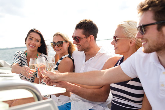 smiling friends with glasses of champagne on yacht